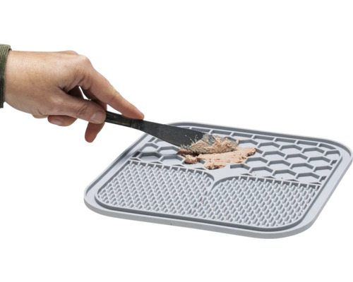 Graue Futtermatte mit Futter und Hand mit Messer