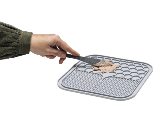 Graue Katzennapfmatte mit Futter und Hand mit Spatel