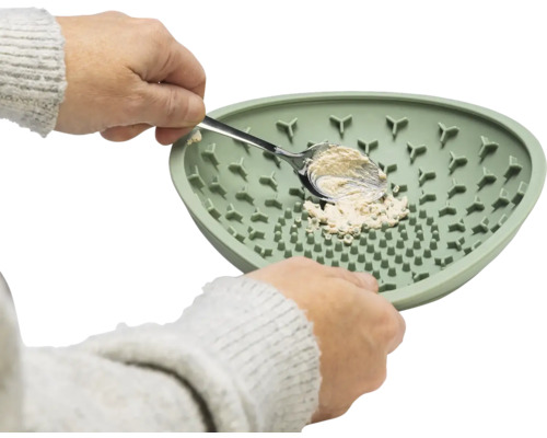 Person füllt Futternapf für Haustiere mit einem Löffel