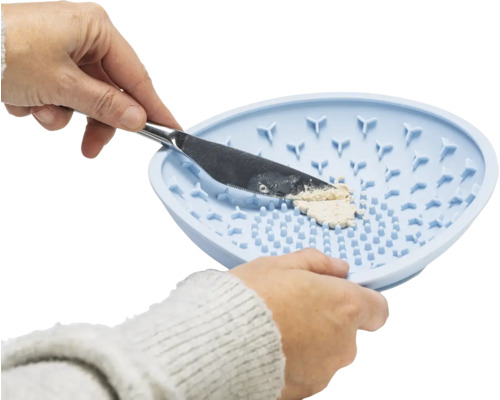 Mains nettoyant les pinceaux avec du savon sur un tapis en silicone