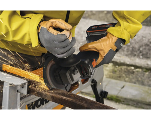 Une personne utilise une meuleuse d''angle sans fil pour couper du métal, produisant des étincelles.