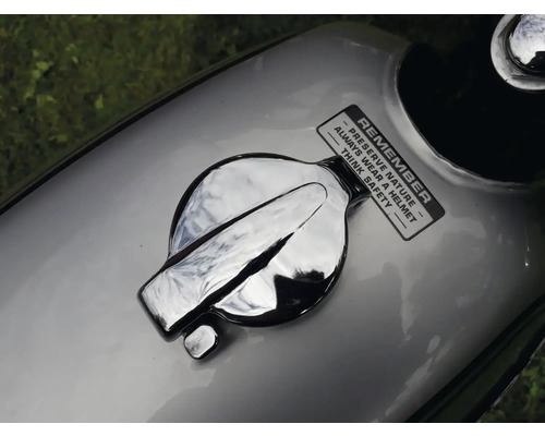 Vue détaillée du réservoir de carburant d''une moto avec un bouchon de réservoir chromé et un autocollant rappelant la protection de la nature et la sécurité