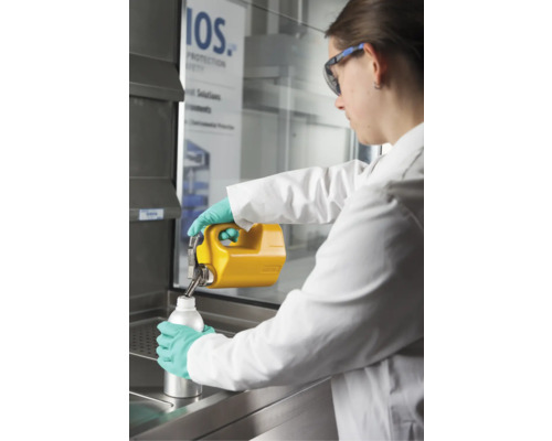 Eine Person füllt eine Flüssigkeit aus einem Kanister in eine Flasche in einem Labor