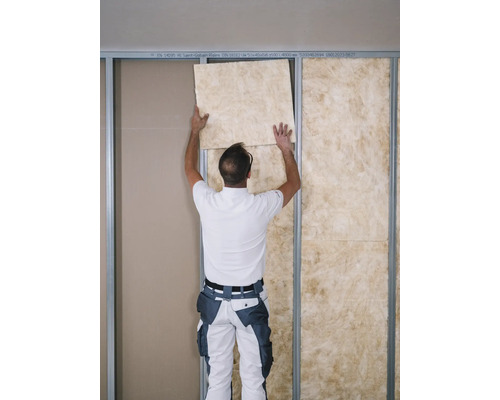 Ein Mann bringt eine Dämmplatte in einem Trockenbaurahmen an