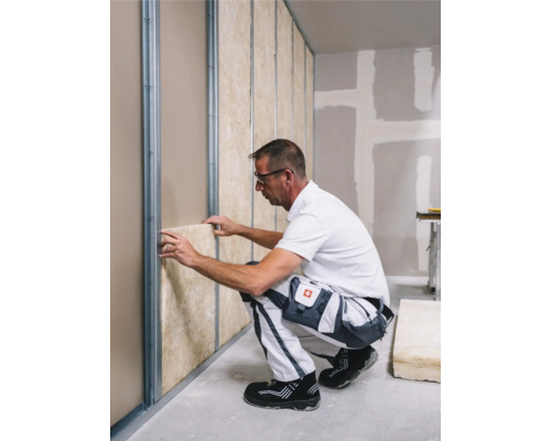 Artisan installant des cloisons sèches avec isolation et profilés métalliques