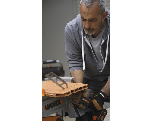 Un homme scie une brique avec une scie de table Worx.