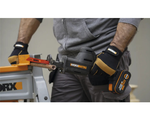 Scie sabre à batterie coupant un tube de cuivre sur un établi