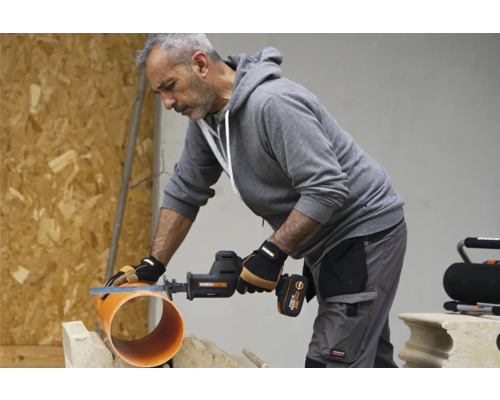 Un artisan coupe un tuyau avec une scie sabre sans fil