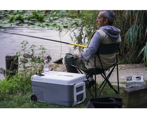Pêcheur assis avec une canne à pêche à côté d''une glacière au bord du lac