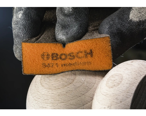 Bosch Schleifpad wird von einer Hand mit Schutzhandschuh gehalten
