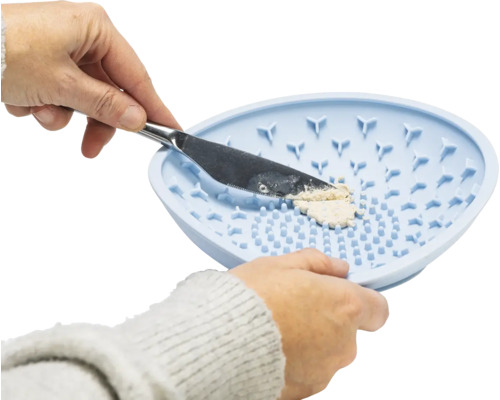 Une personne presse une crème à travers un tamis en silicone avec un couteau