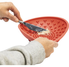 Eine Person reibt mit einem Messer Knoblauch in einer Knoblauchreibe