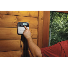 Une personne utilise un ordinateur d''irrigation sur un mur en bois.