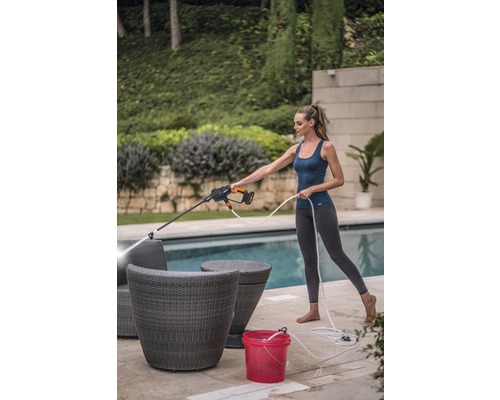 Femme nettoyant des meubles de jardin avec un nettoyeur haute pression à l''extérieur.