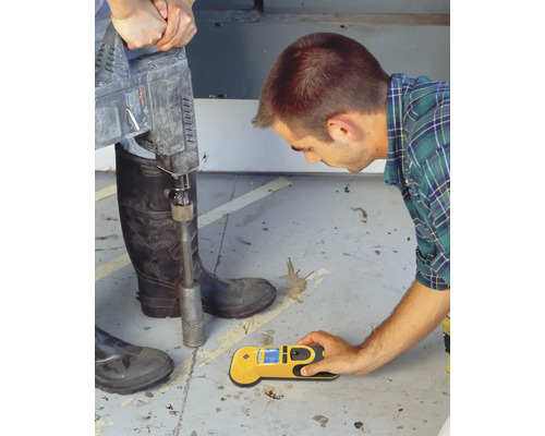 Mann lokalisiert mit einem Ortungsgerät Leitungen im Boden, während eine zweite Person mit einem Abbauhammer arbeitet.