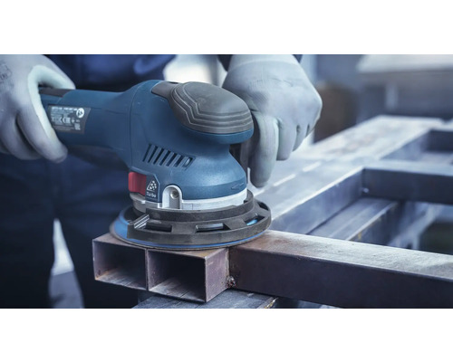 Artisan ponçant du métal avec une ponceuse excentrique.