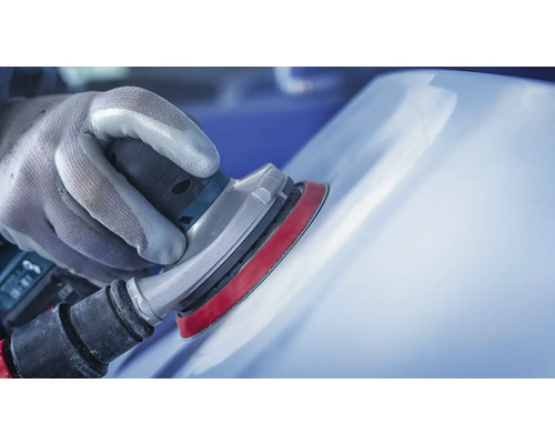 Main gantée ponçant une surface avec une ponceuse excentrique