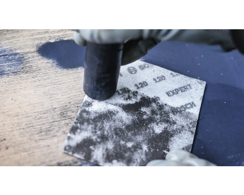 Schleifen einer Holzoberfläche mit Schleifpapier und Schleifklotz