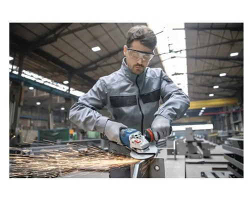 Ein Arbeiter mit Schutzbrille verwendet einen Winkelschleifer auf Metall und erzeugt Funken.