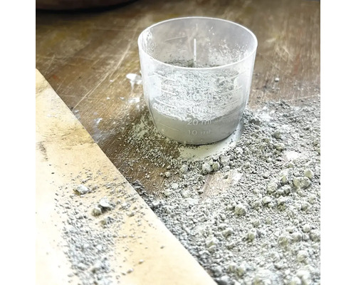 Gobelet doseur avec du ciment sur une surface en bois