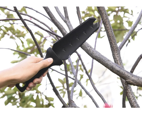 Une main tient une hache de jardin multifonctionnelle utilisée sur une branche