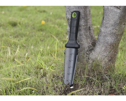 Outil de jardinage avec manche et échelle de mesure appuyé contre un arbre