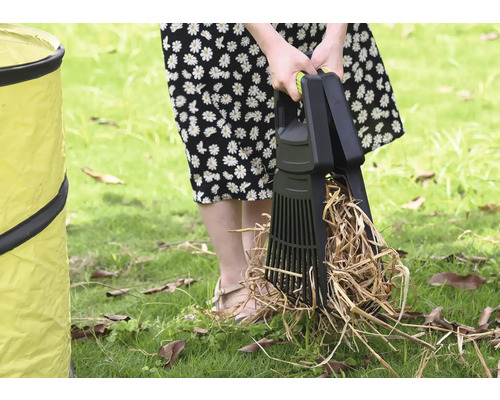 Une personne utilise un ramasse-feuilles pour ramasser les feuilles sur une pelouse à côté d''un sac de jardin.
