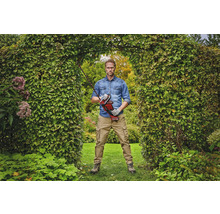 Un homme se tient dans une arche de jardin et tient un taille-haie sans fil.