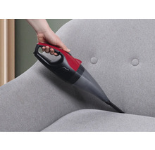 Handstaubsauger bei der Reinigung eines grauen Stoffsofas