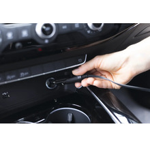 Eine Hand steckt ein Kfz-Ladekabel in eine 12-Volt-Steckdose im Auto.