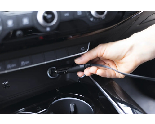 Eine Hand steckt ein Kfz-Ladekabel in eine 12-Volt-Steckdose im Auto.