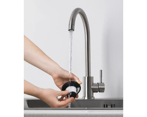Eine Person reinigt einen Staubsaugerfilter unter einem Wasserhahn