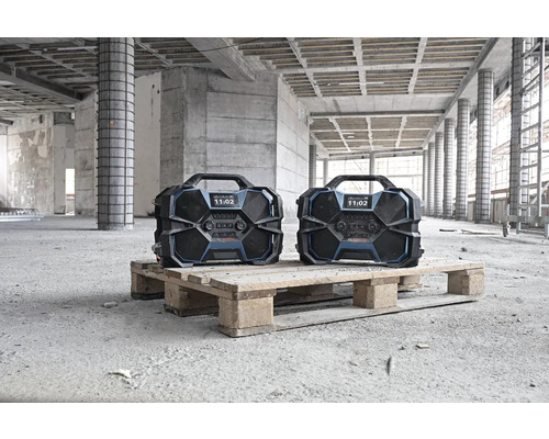 Zwei tragbare Bosch-Baustellenradios auf einer Palette in einem Rohbau.