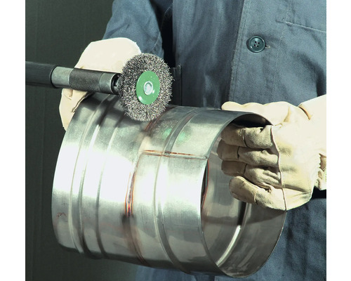 Une personne utilise une brosse métallique pour nettoyer un tuyau métallique.