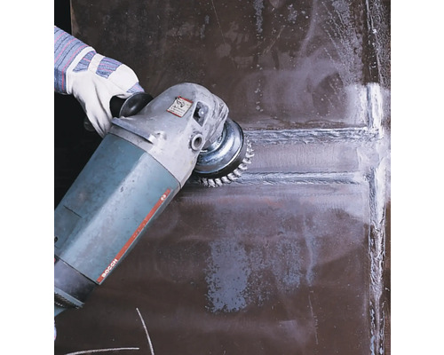 Une personne utilise une brosse métallique sur une meuleuse pour le travail des métaux.