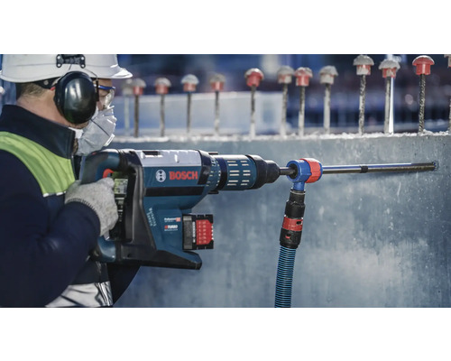 Ein Arbeiter bohrt mit einem Bohrhammer ein Loch in Beton. Bosch Logo.