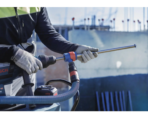 Handwerker mit Bohrhammer und Staubsaugeraufsatz auf einer Baustelle