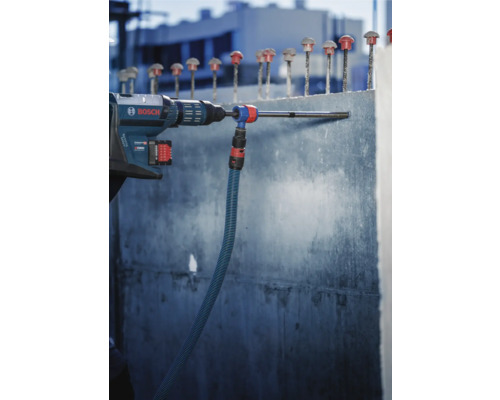 Logo Bosch. Une perceuse perce un trou dans un mur en béton avec un aspirateur.