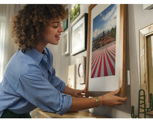 Femme accrochant une photo encadrée au mur
