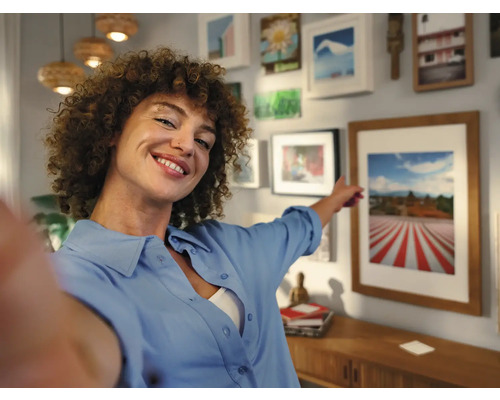 Frau zeigt auf gerahmtes Bild in einem hellen Wohnzimmer