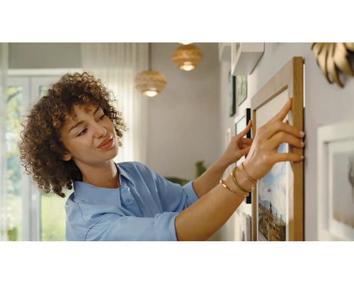Une femme aligne des cadres photo sur le mur. Décoration pour l''aménagement intérieur.