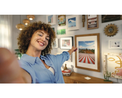 Femme pointant une galerie de photos au mur dans un salon