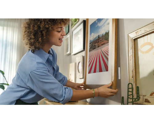 Femme accrochant une image encadrée à un mur