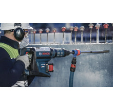 Ein Arbeiter bohrt mit einer Bohrmaschine Löcher in eine Betonwand. Bosch Logo.
