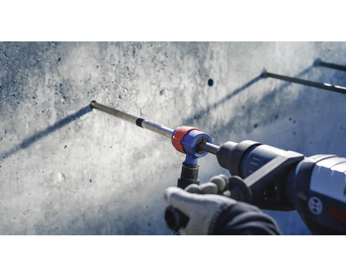 Eine Bohrmaschine bohrt ein Loch in eine Betonwand mit einem angeschlossenen Staubsauger.
