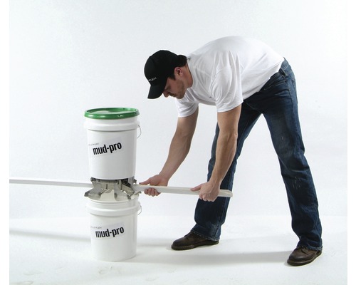 Une personne coupe un matériau de construction sèche avec un outil Mud-Pro entre deux seaux.