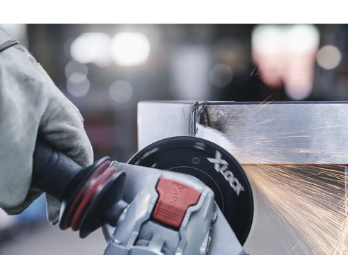 Eine Person schleift Metall mit einem Winkelschleifer, bei dem Funken entstehen.