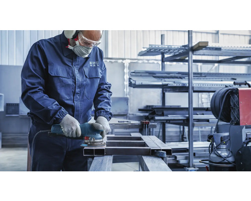 Ein Handwerker schleift Metall mit einem Exzenterschleifer, ausgestattet mit Sicherheitsausrüstung.