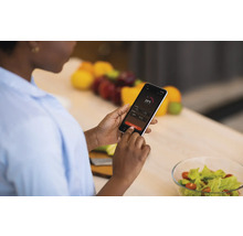 Femme utilisant un smartphone avec affichage de la température dans la cuisine