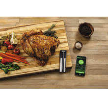 Scène avec poulet rôti, légumes, thermomètre à viande et smartphone sur une planche à découper